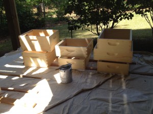 After assembling the hive bodies and supers, they are ready for painting; first with an oil based primer and then an oil based top coat. The joints have been sealed with caulk to ensure uniform painting and to prevent wood rot.